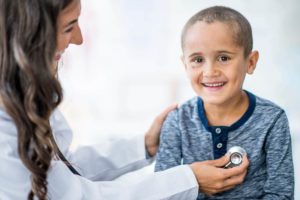 doctor using a stethoscope to lesson to child's heart
